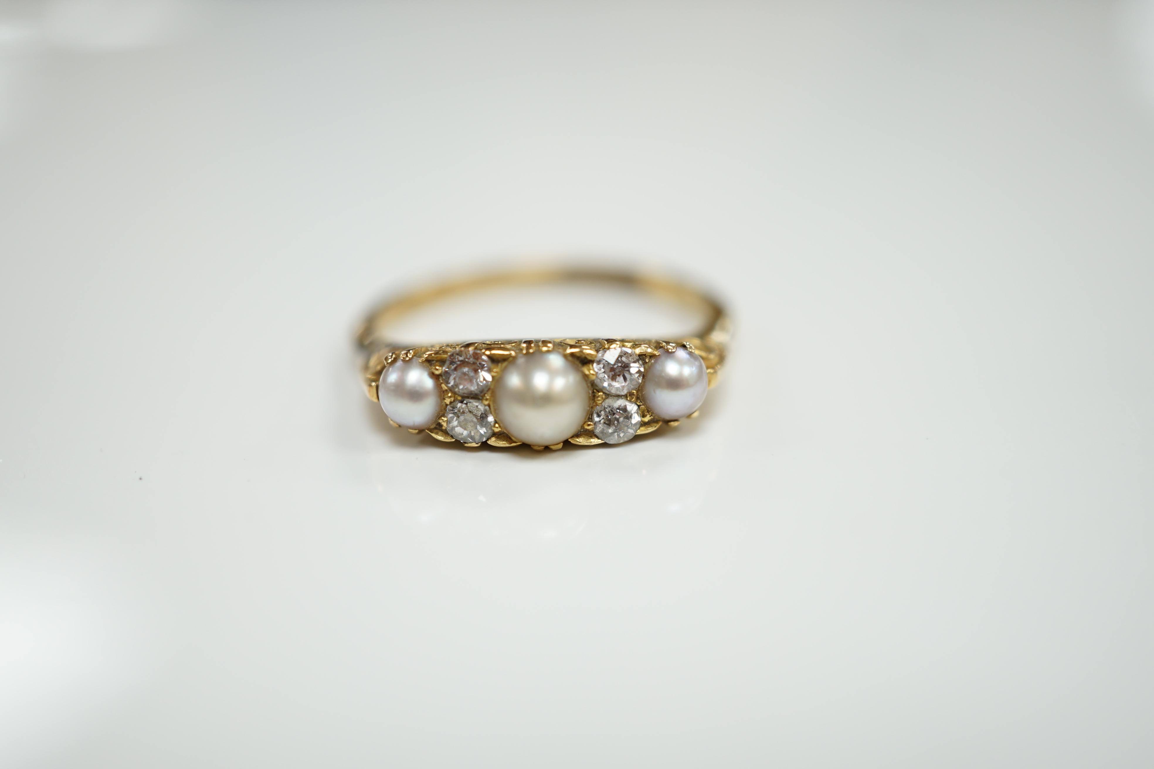 An early 20th century 18ct and plat, three stone split pearl and four stone diamond set half hoop ring, size P, gross weight 3.2 grams.